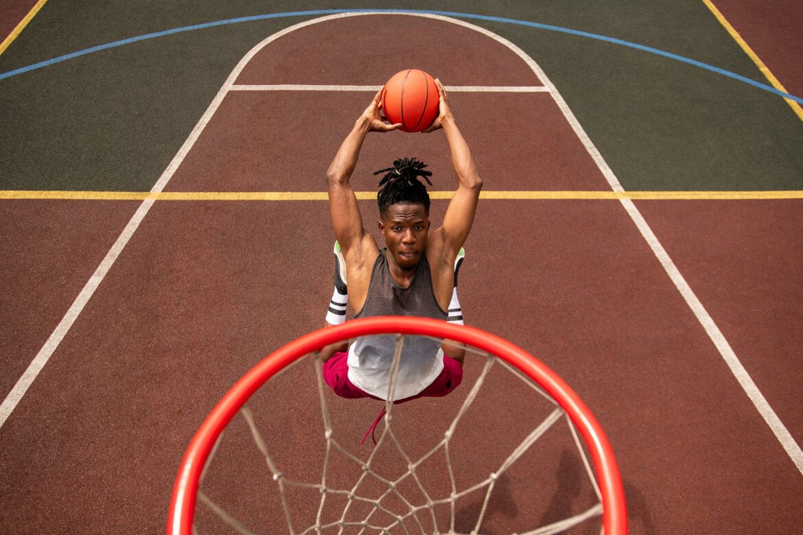 African young basketballer making effort while throwing ball in basket